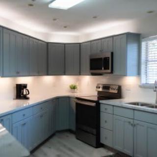 A modern kitchen with blue cabinetry and stainless steel appliances.