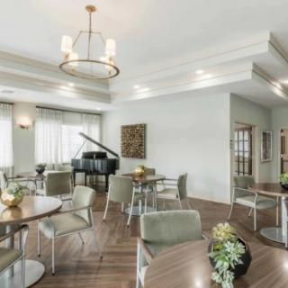 A spacious dining area featuring a grand piano, modern tables and chairs, with elegant lighting and decor.