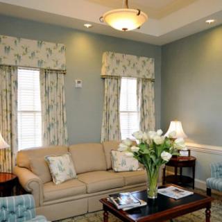 A cozy living room with a beige sofa, floral curtains, and elegant lighting.