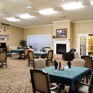 A well-lit dining area with multiple tables and chairs, featuring a fireplace and decorated walls.