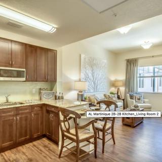 A modern apartment featuring an open kitchen and living room with wooden flooring and bright lighting.