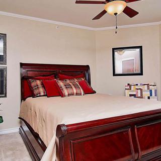 A cozy bedroom with a dark wooden bed, neutral bedding, and a ceiling fan.