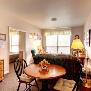 A cozy living room with a small dining area, featuring comfortable furniture and warm lighting.