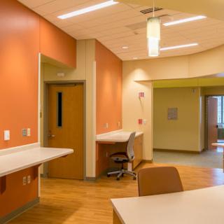 A modern and inviting interior of a medical facility featuring orange walls and practical furniture.