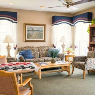 A cozy living room with stylish decor, featuring a sofa, armchair, coffee table, and decorative elements such as lamps and a painting.
