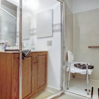 A spacious and modern bathroom featuring a shower, vanity sink, and accessible seating.