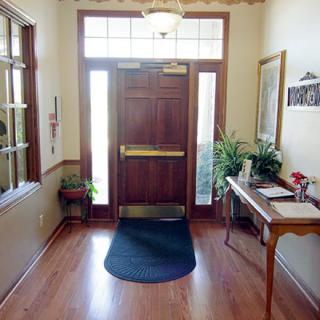 A well-lit entryway with a wooden door, potted plants, and a small table.