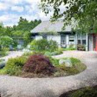 A charming house surrounded by a lush garden with winding pathways and various plants.