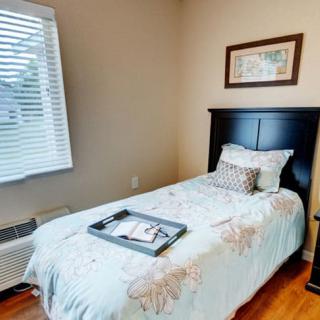 A cozy bedroom with a single bed featuring a decorative pillow and artwork on the wall.
