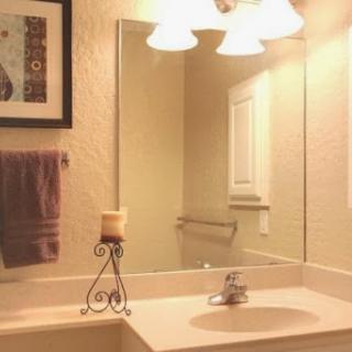 A well-lit bathroom featuring a sink, mirror, decorative candle, and towel.