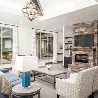 A modern living room with a brick fireplace, elegant chandelier, and comfortable seating arrangement.