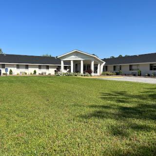 A spacious residential house set against a clear blue sky, featuring a well-manicured front yard.