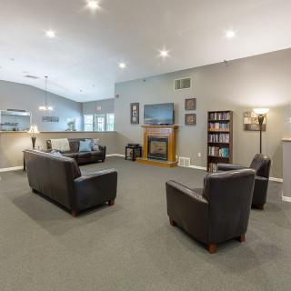 A spacious living room with modern furniture, featuring a fireplace and ample lighting.