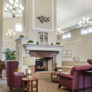 A cozy living room with a large fireplace, elegant lighting fixtures, and comfortable seating.