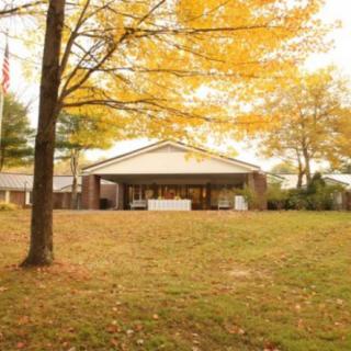 A building surrounded by autumn trees with fallen leaves on the grass.