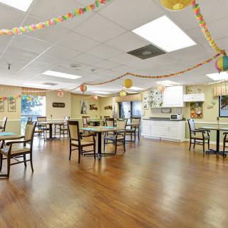 A decorated community dining room with tables and chairs arranged neatly.