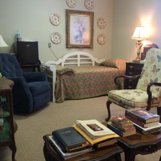 A cozy living room with a daybed, armchair, and a collection of books on a table.