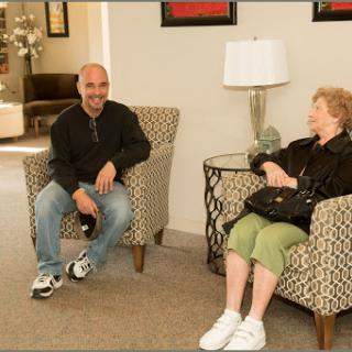 A man and a woman seated in a cozy indoor setting, engaging in conversation.