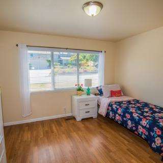 A cozy bedroom with a single bed and natural lighting through a window.
