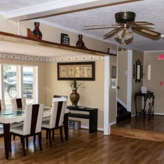 A stylish dining room with a wooden floor, elegant dining table, and ceiling fan.