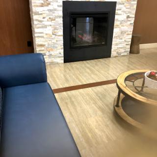 A cozy living room featuring a blue couch, round coffee table, and a modern stone fireplace.