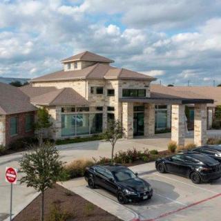 A modern building with a parking lot in the foreground under a cloudy sky.