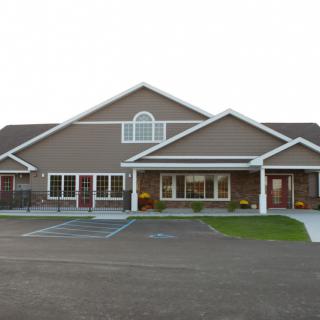 A symmetrical residential building with a driveway and parking spaces in front.