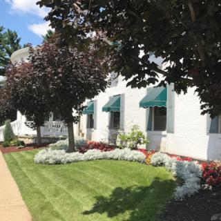 A well-maintained building exterior featuring lush landscaping and green awnings on a sunny day.