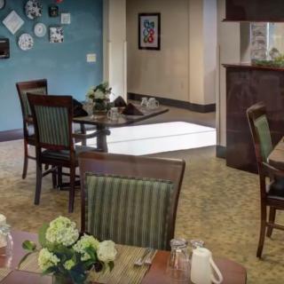 A cozy dining area with neatly arranged tables and chairs, decorated with flowers.