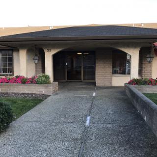 The entrance of a well-maintained building surrounded by colorful flowers.