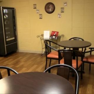 A cozy break room with tables and chairs, featuring a vending machine and a wall clock.