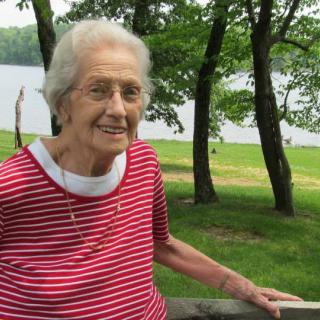 An elderly woman enjoying a day at the park by the lake.
