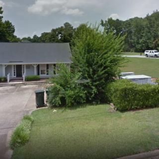 A suburban house with a well-maintained lawn and surrounding trees.
