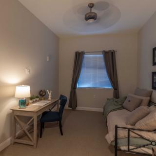 Cozy bedroom with a neatly arranged desk and bed, featuring soft lighting and elegant curtains.