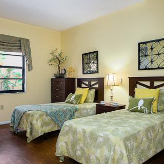 A well-decorated bedroom with two single beds, complete with matching bedspreads, wall art, and a bedside lamp.