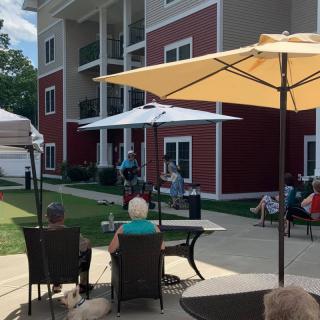 People seated outdoors enjoying a live performance beside a residential building.