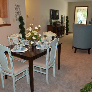 A cozy dining and living area featuring a neatly set dining table with four chairs and elegant decor.