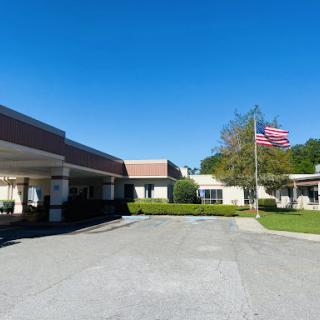 A healthcare facility with a clear blue sky and the American flag waving in front.
