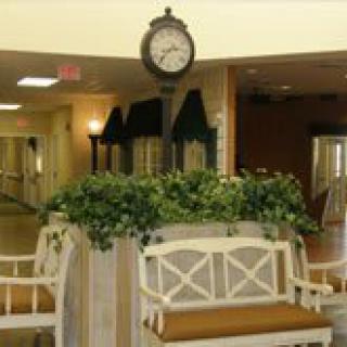 A cozy interior space featuring a decorative clock and seating area with greenery.