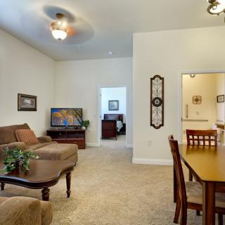 A cozy living room with a dining area, featuring a sofa, television, and a wooden dining set.