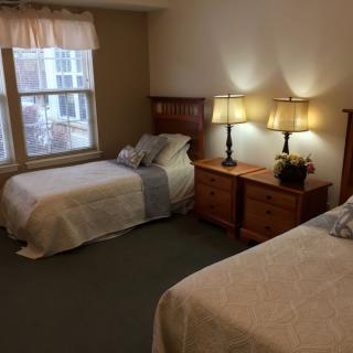 A cozy bedroom with two beds, nightstands, and soft lighting from lamps.