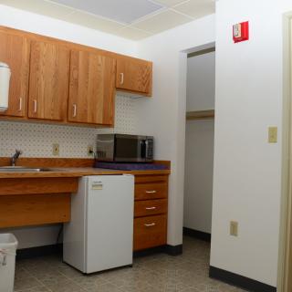 A small apartment kitchen with wooden cabinets, a microwave, and a mini fridge.