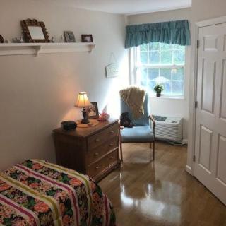 A cozy bedroom with a single bed, dresser, and a window allowing natural light to flow in.