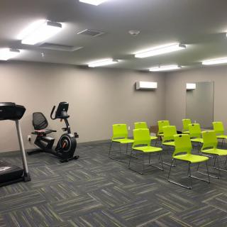 A multi-purpose room with gym equipment and arranged chairs.