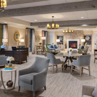 A spacious and cozy living room with comfortable seating, a warm fireplace, and elegant chandeliers.
