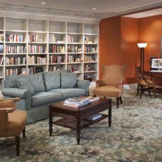 A cozy library room with a sofa, chairs, and bookshelves filled with books.