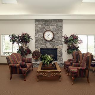 A cozy living room with a stone fireplace, clock, and comfortable seating arrangement.