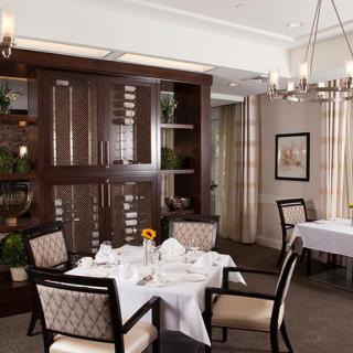 An elegant dining area with a neatly arranged table setting, complete with a chandelier overhead.