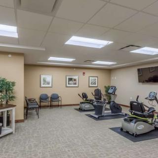 A gym with exercise machines and seating in a well-lit room.