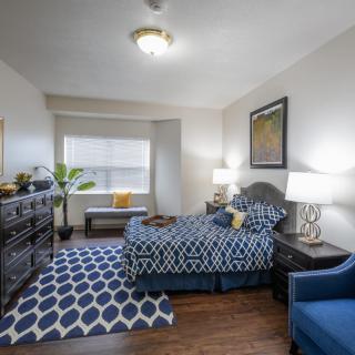 A well-decorated bedroom featuring a stylish blue and white theme with a comfortable bed, patterned rug, and elegant lamps.